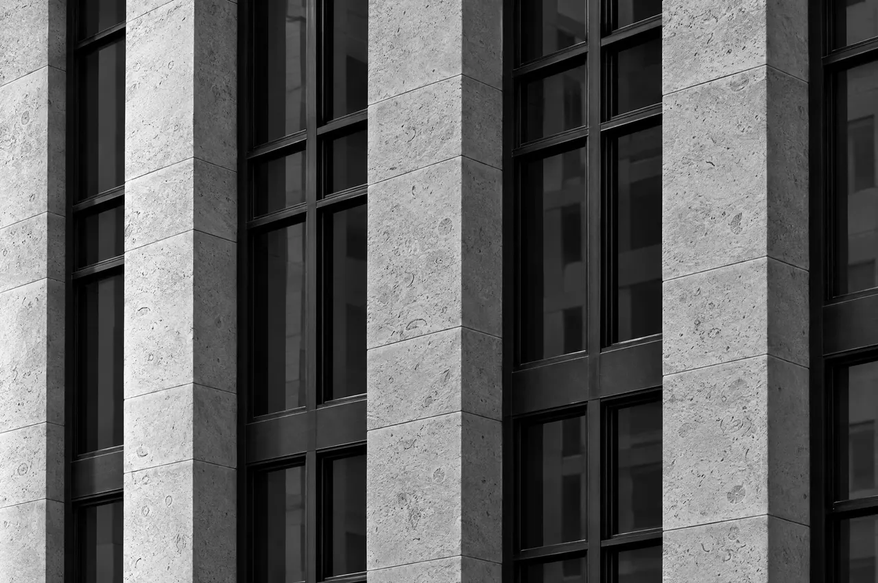 Indiana limestone facade meeting a grid of black steel window frames